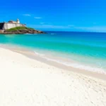 Praia do Forte em Cabo Frio com mar azul e Forte São Mateus.