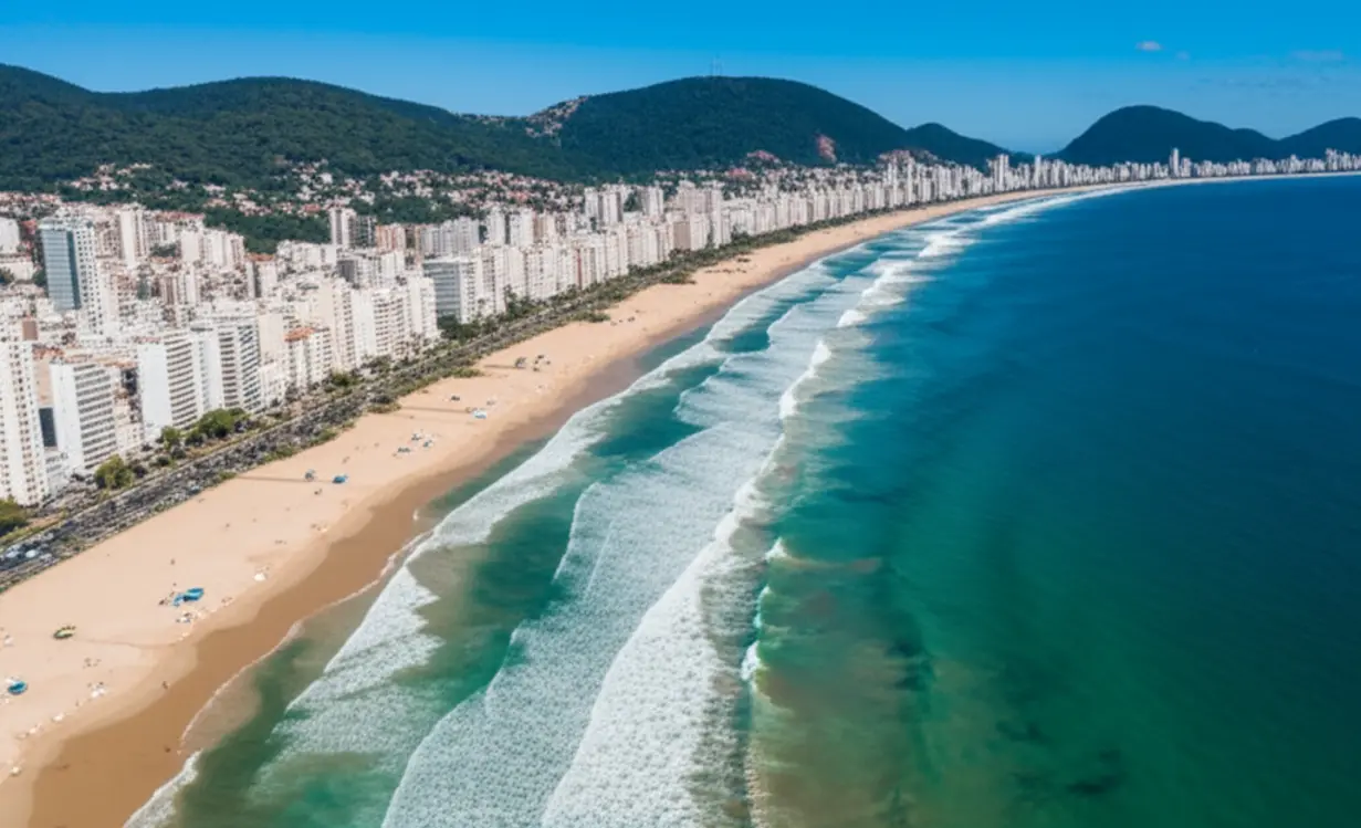 Vista aérea espetacular da orla de Guarujá com águas azuis e edifícios modernos.