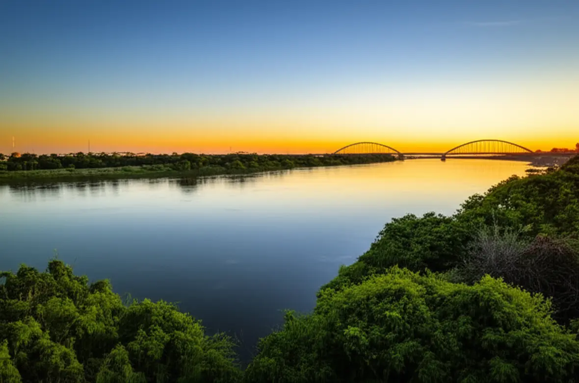 Vista panorâmica do Rio São Francisco em Petrolina com a ponte e o pôr do sol ao fundo.