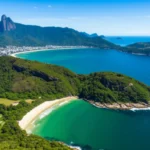 Vista aérea da costa de São Sebastião mostrando o encontro do mar azul com a mata verde.