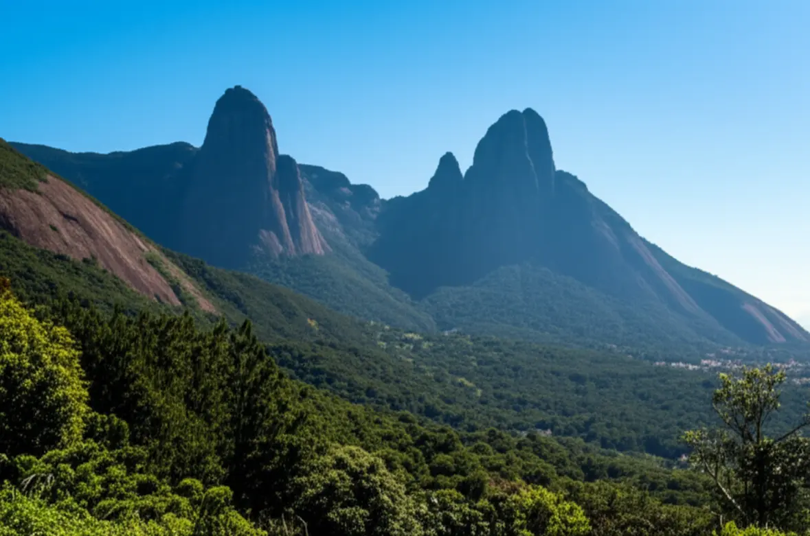 Paisagem majestosa do pico Dedo de Deus em Teresópolis com céu azul e floresta verde.
