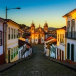 Foto realista da ladeira de Ouro Preto com casarões coloniais e igreja barroca sob luz de fim de tarde.