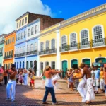 Casarões coloridos do Pelourinho, Salvador, Brasil, com pessoas dançando na rua.
