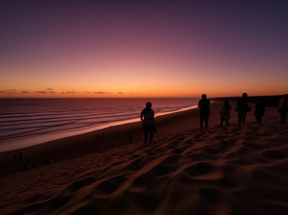 Silhuetas de pessoas assistindo ao pôr do sol na duna de areia em Canoa Quebrada.