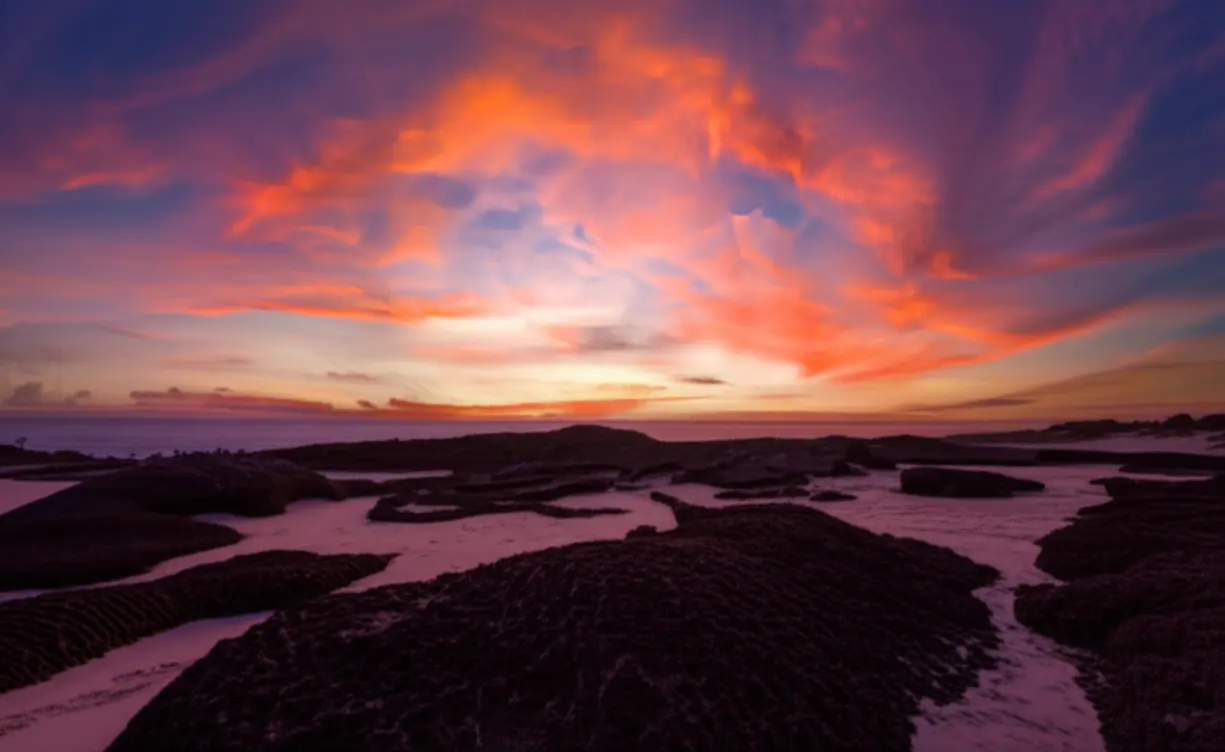 Céu alaranjado no pôr do sol sobre as dunas petrificadas de Tourinhos, RN.