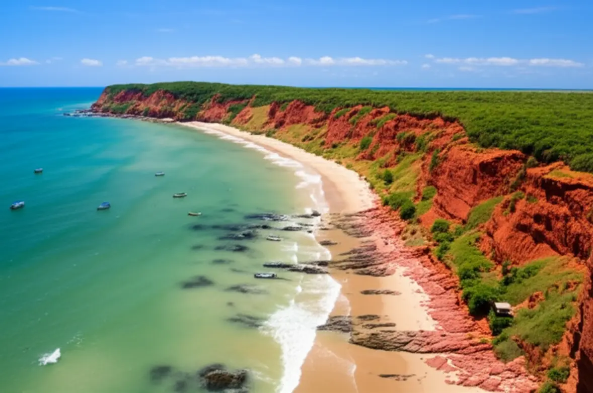 Vista aérea panorâmica da Praia de Pipa com falésias avermelhadas e mar verde-esmeralda.