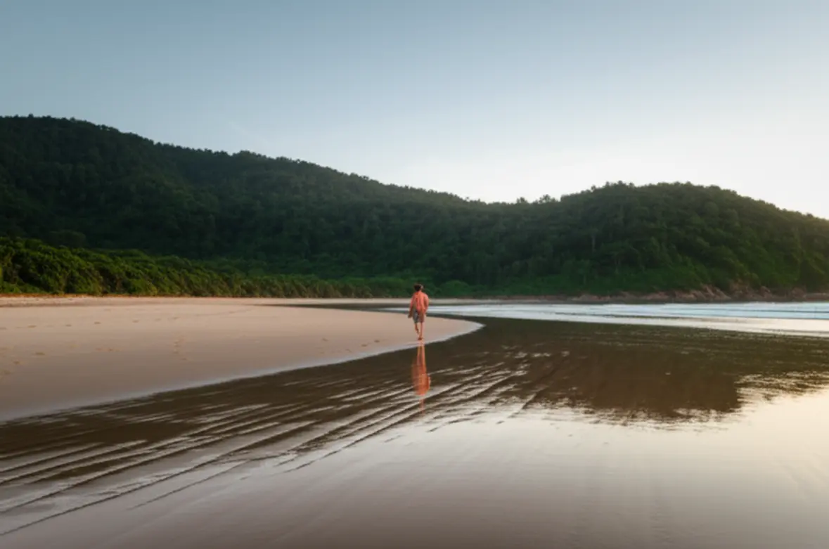 Pessoa caminhando sozinha na Praia do Rosa durante a baixa temporada.