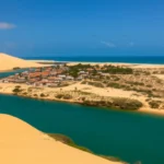 Vista aérea da península de Galinhos mostrando o encontro do rio com o mar e dunas.