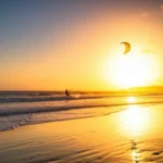 Pôr do sol dourado em São Miguel do Gostoso com kitesurfer.