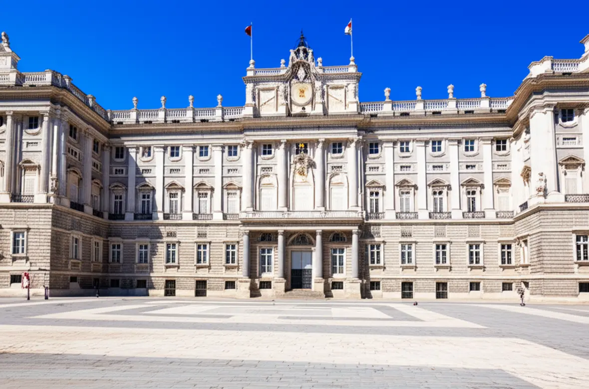 Fachada majestosa do Palácio Real de Madri sob um céu azul claro.