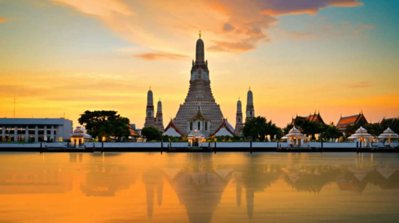 Vista panorâmica do templo Wat Arun refletido no rio Chao Phraya ao pôr do sol.
