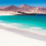 Vista panorâmica de Bahía Inglesa com águas turquesas e montanhas desérticas ao fundo.