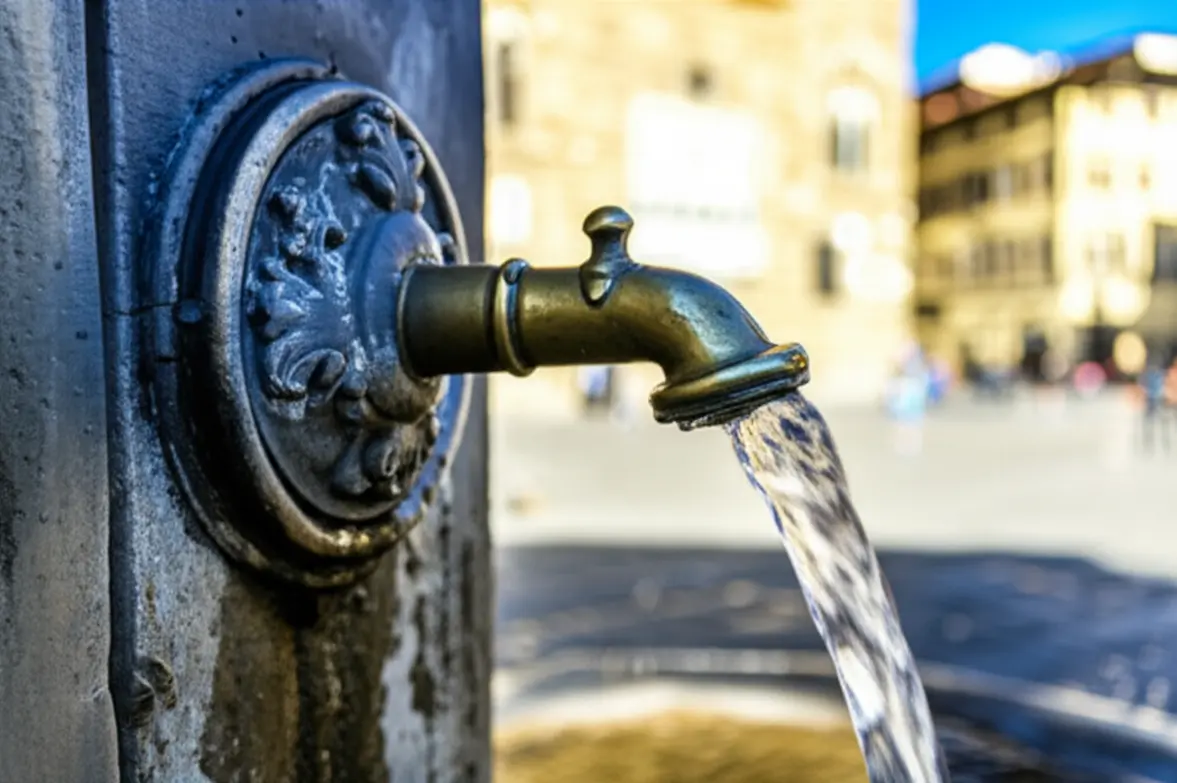 Fonte de água potável em pedra em uma praça ensolarada de Florença.