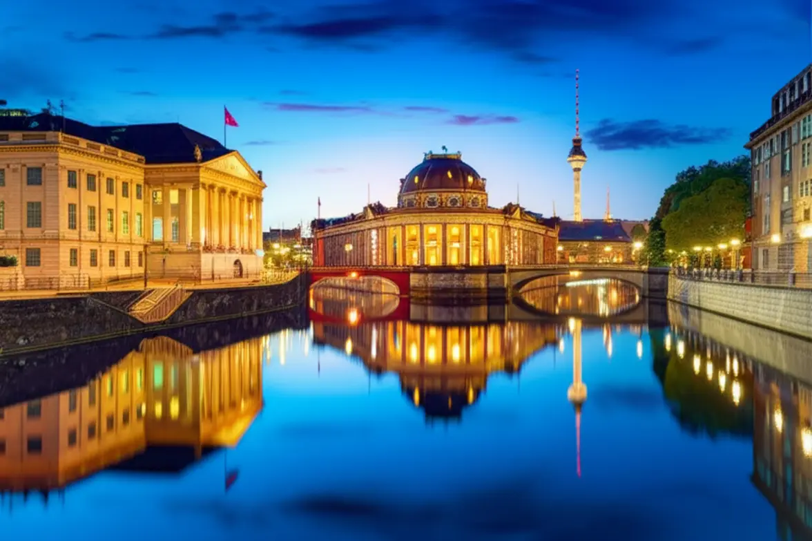 Vista panorâmica da Ilha dos Museus refletida nas águas calmas do Rio Spree ao entardecer.