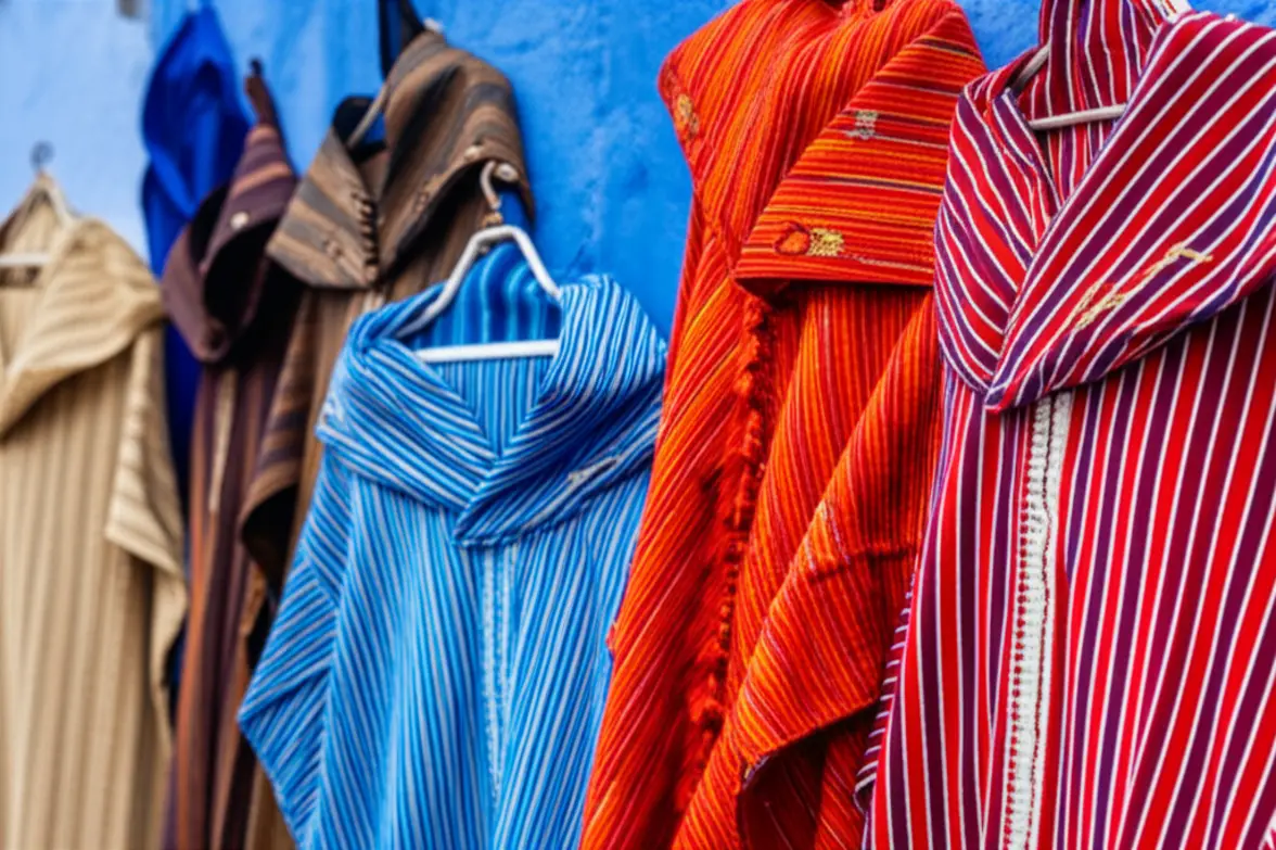 Mercado de rua em Chefchaouen com mantas coloridas e artesanato local exposto.