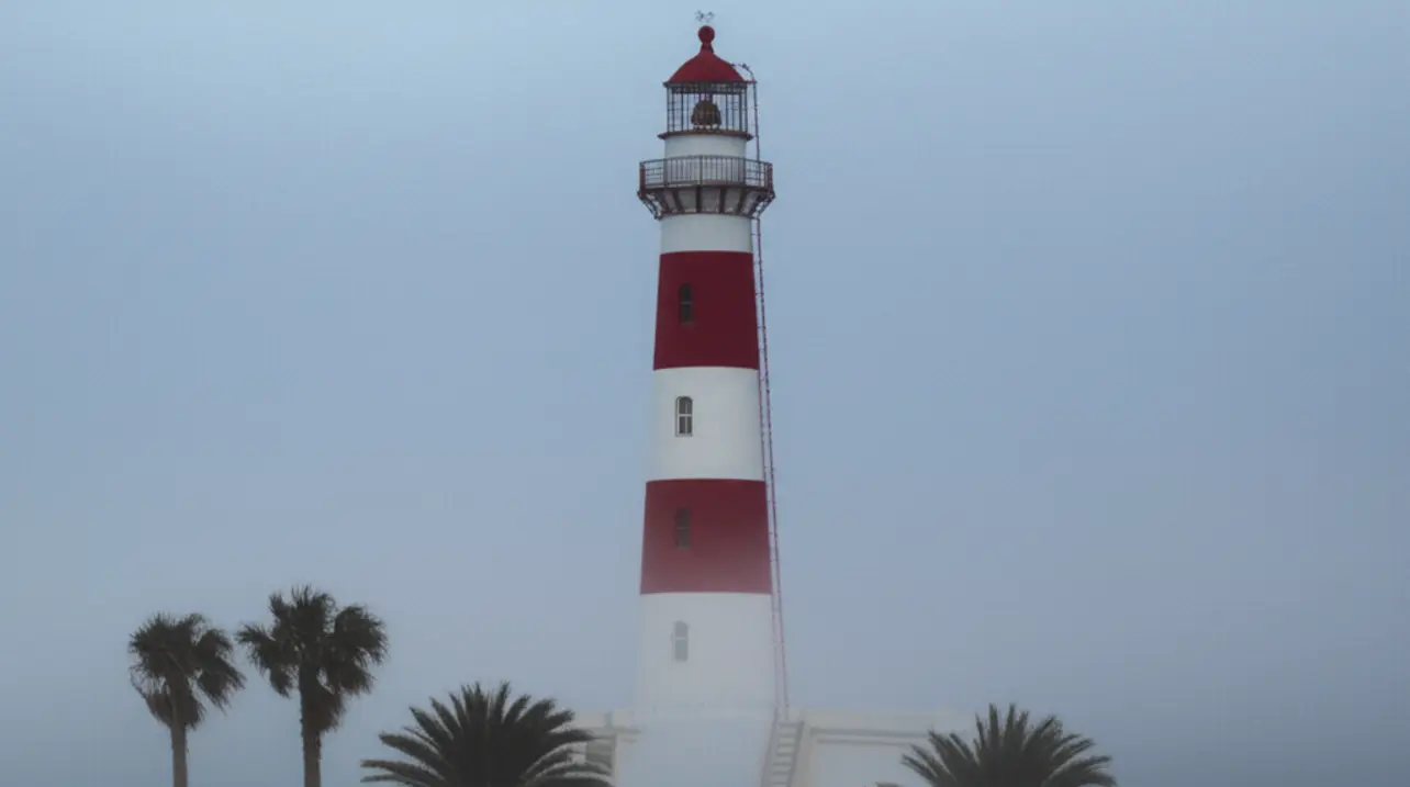 O icônico farol vermelho e branco de Swakopmund envolto pela névoa matinal característica.