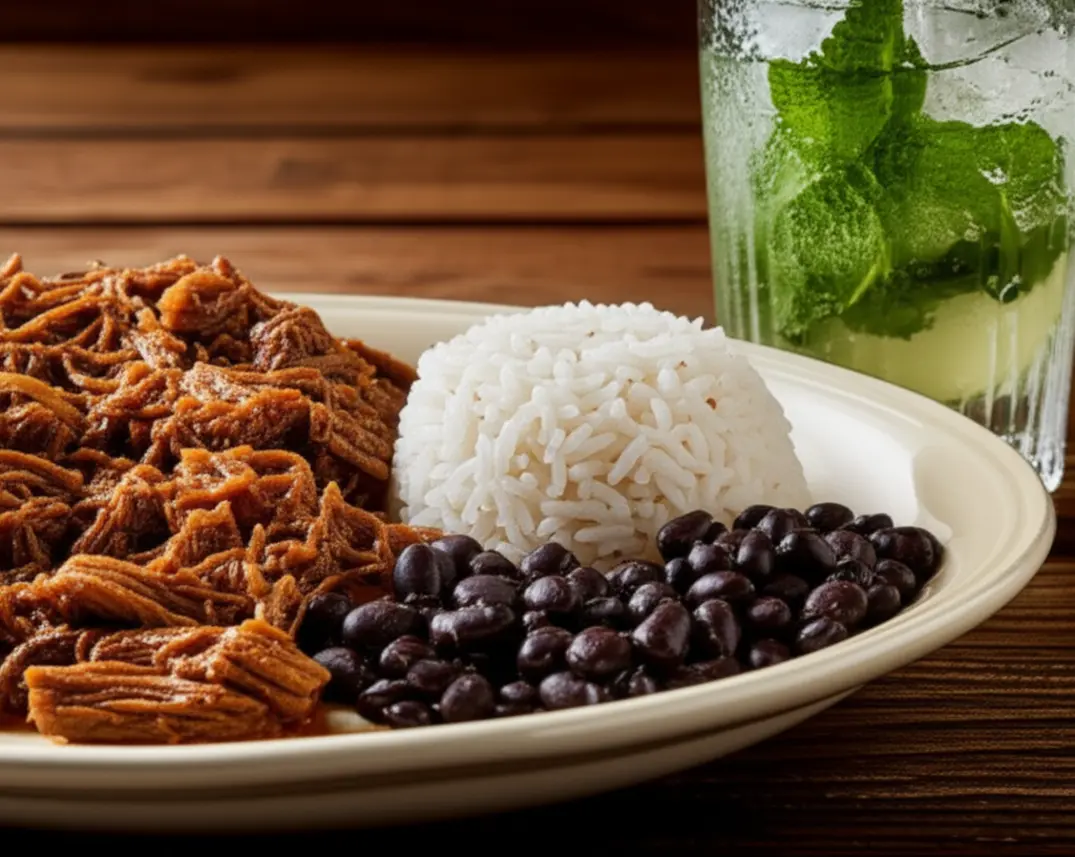 Prato de Ropa Vieja acompanhado de um Mojito refrescante em uma mesa de madeira.