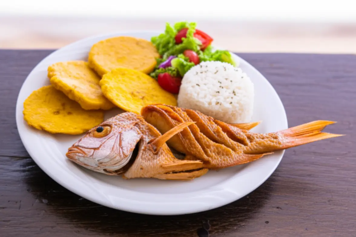 Prato típico de peixe frito com arroz de coco e patacones.