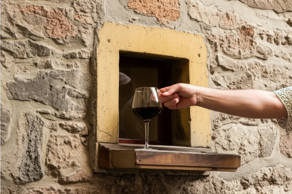 Uma tradicional janelinha de vinho em uma parede de pedra rústica em Florença com uma taça de vinho.