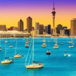 Skyline de Auckland com a Sky Tower e veleiros no porto Waitematā.