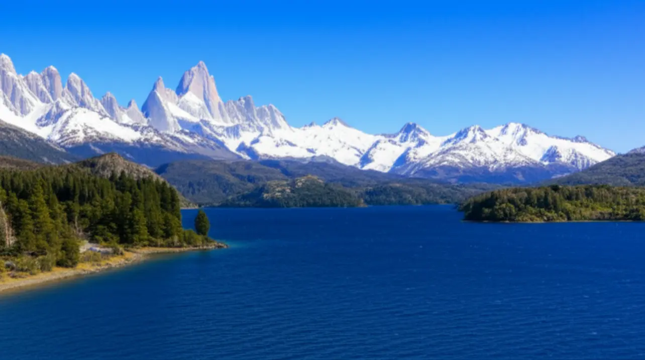 Paisagem de Bariloche com lago azul e montanhas cobertas de neve ao fundo.