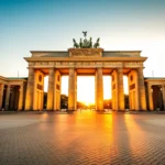 O Portão de Brandemburgo em Berlim iluminado durante o pôr do sol, sem pessoas ao redor.