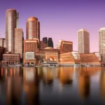 Vista panorâmica do skyline de Boston refletido no Rio Charles durante o pôr do sol.