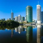 Skyline de Brisbane com prédios modernos e o Rio Brisbane sob um pôr do sol dourado.