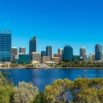Vista aérea do horizonte de Perth com o Rio Swan e parques verdes sob sol forte.