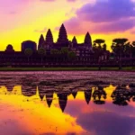 O nascer do sol dourado atrás das cinco torres de Angkor Wat refletidas no lago.