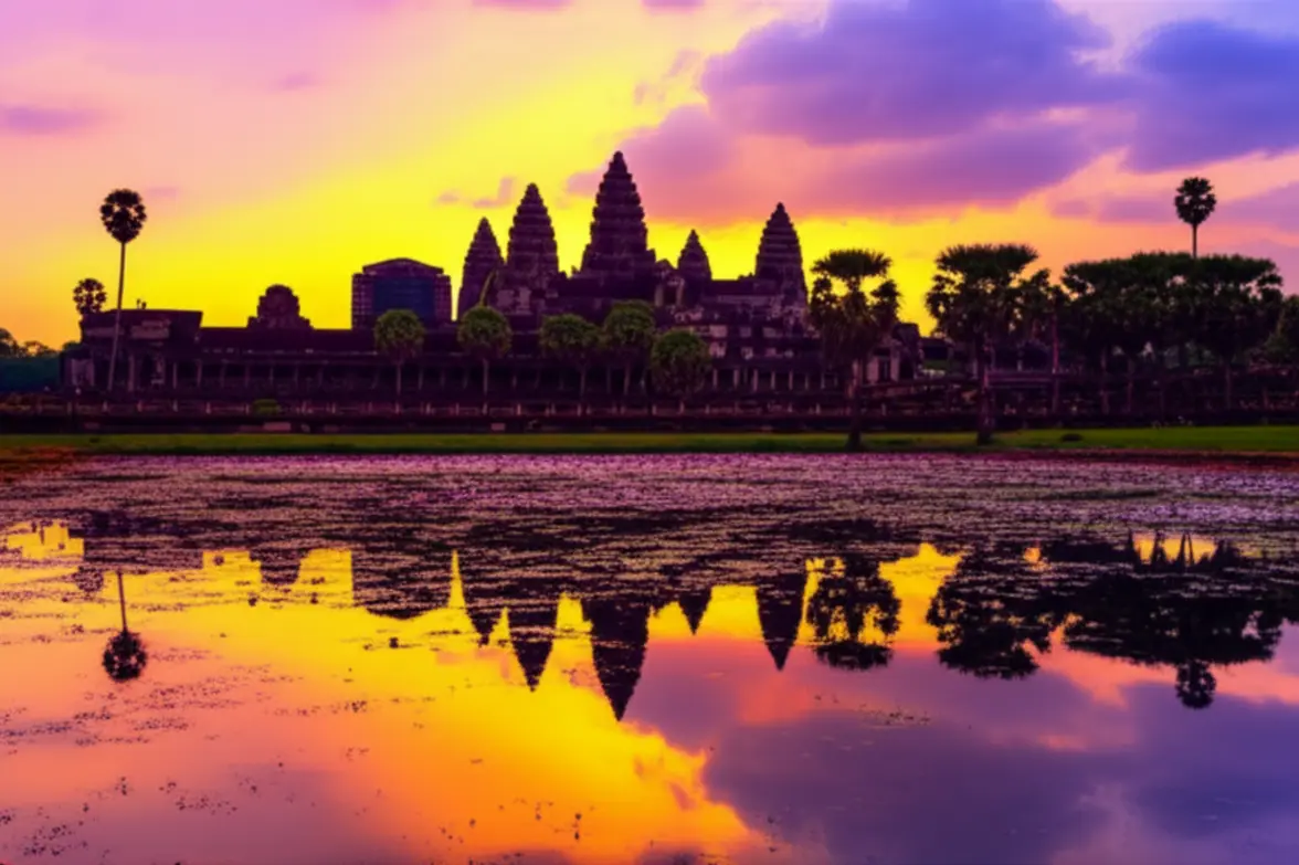 O nascer do sol dourado atrás das cinco torres de Angkor Wat refletidas no lago.