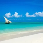 Praia paradisíaca em Zanzibar com areia branca e barco tradicional Dhow.
