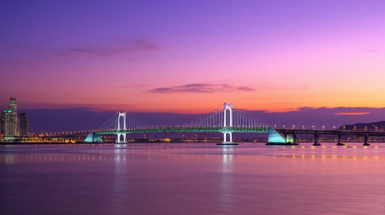 A ponte Diamond Bridge (Gwangan) iluminada sobre o mar em Busan durante o pôr do sol.