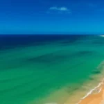 Vista aérea paradisíaca da Praia de Santa Maria na Ilha do Sal com areia dourada e mar azul turquesa.