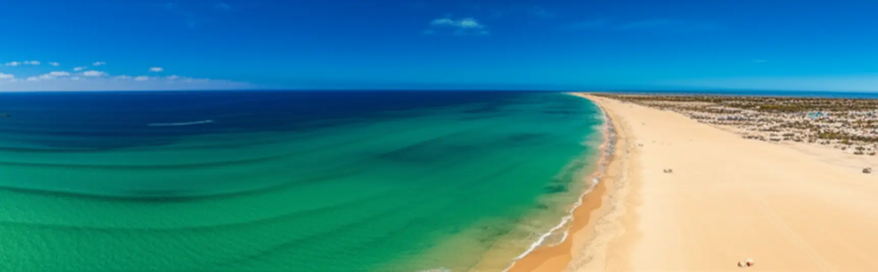 Vista aérea paradisíaca da Praia de Santa Maria na Ilha do Sal com areia dourada e mar azul turquesa.