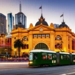 Fachada da Flinders Street Station em Melbourne com um bonde passando à frente.