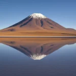 O imponente Vulcão Licancabur refletido em uma lagoa no Deserto do Atacama ao pôr do sol.