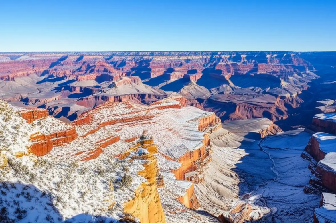 Vista do Grand Canyon com as bordas cobertas por neve sob um céu limpo.