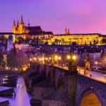 Vista panorâmica da Ponte Carlos e do Castelo de Praga ao pôr do sol.