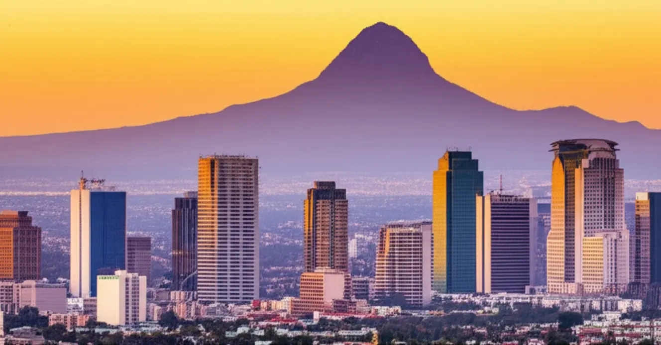 Panorama da cidade de Monterrey com o icônico Cerro de la Silla ao fundo sob um pôr do sol dourado.