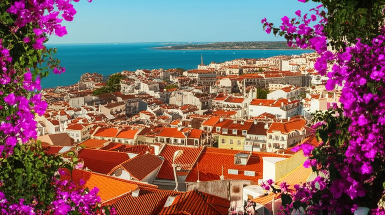 Vista panorâmica do Miradouro de Santa Luzia em Lisboa com flores vermelhas e telhados antigos.