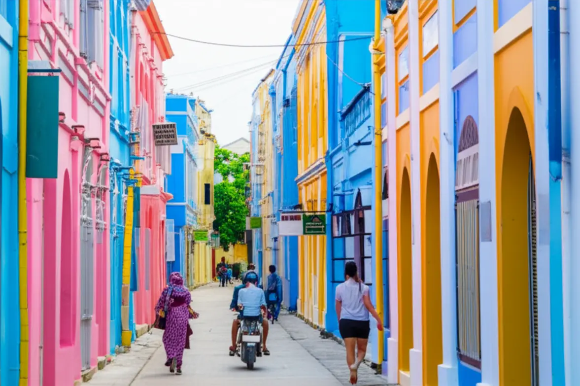 Rua estreita com prédios coloridos e motocicletas estacionadas em Malé.