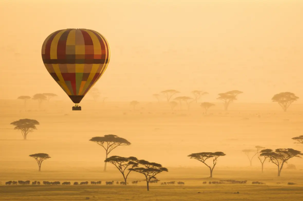 Balão de ar quente sobrevoando a savana do Serengeti ao amanhecer.