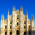Vista frontal da Catedral de Milão (Duomo) em um dia ensolarado com céu limpo.