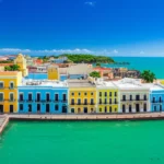 Vista panorâmica da orla de San Juan com prédios coloridos e mar azul.