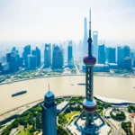 Vista aérea limpa do skyline de Xangai com destaque para a Torre da Pérola do Oriente e o Rio Huangpu.