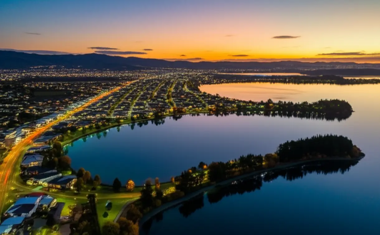 Vista panorâmica do Lago Rotorua e da cidade ao entardecer.